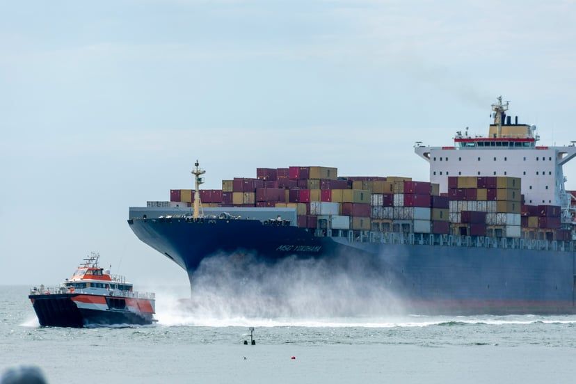 An MSC container ship at sea being pulled by a tugboat