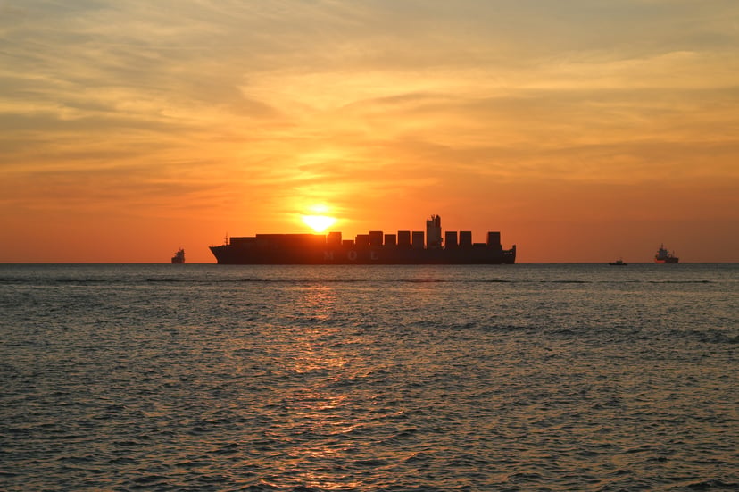 A container ship at sunset on the horizon