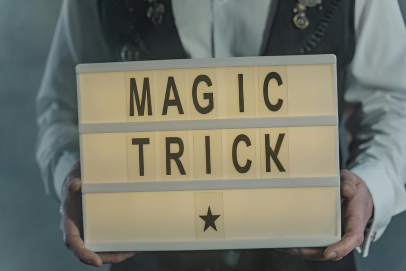 a magician holding a sign saying 'magic trick'