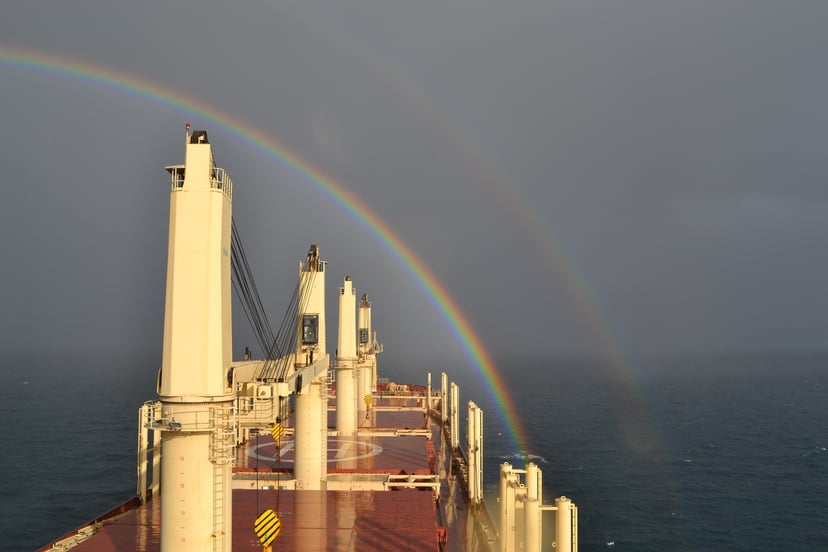A bulk carrier sailing towards a rainbow