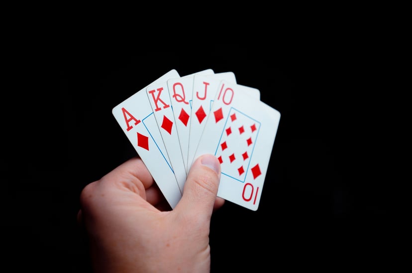 a hand holding the Ace, King, Queen, Jack and Ten of Diamonds