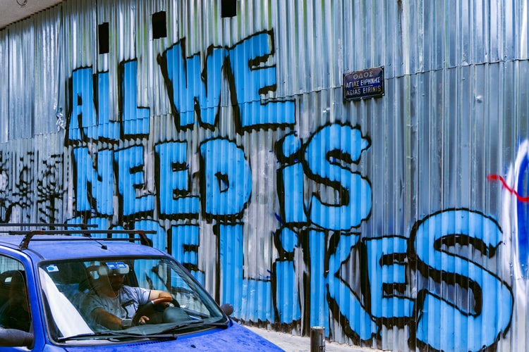 graffiti on a fence saying 'all we need is likes'