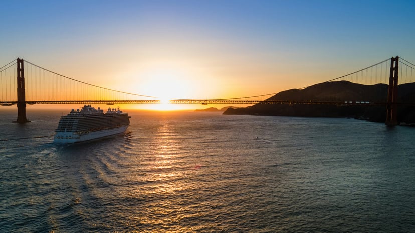a cruise ship sailing towards the Golden Gate Bridge at sunset