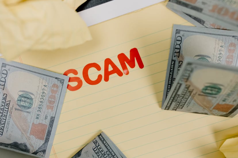 the word scam on a piece of paper surrounded by bank notes