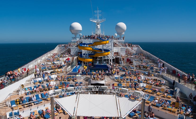 a water slide and numerous passengers on sun loungers on the deck of a cruise ship