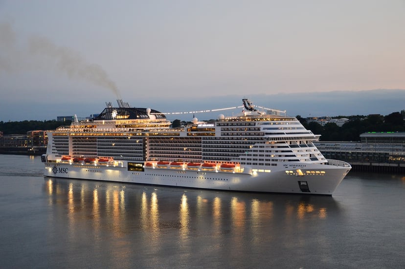 The MSC Meraviglia cruise ship sailing close t land at dusk