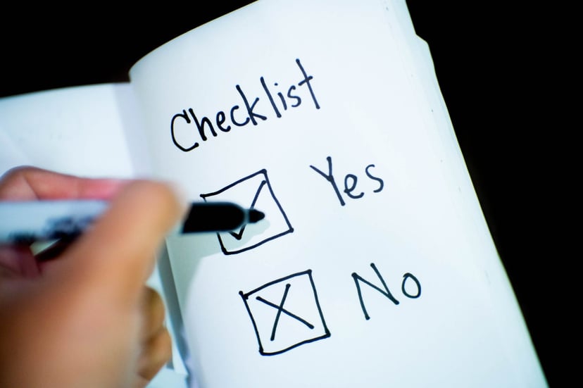 A hand checking boxes next to the words 'yes' and 'no' in a notebook