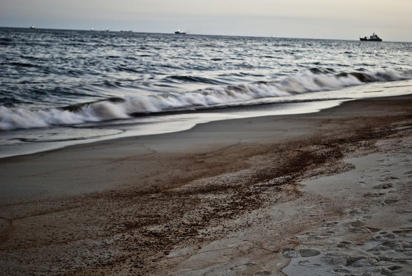 oil on a beach with a ship in the background