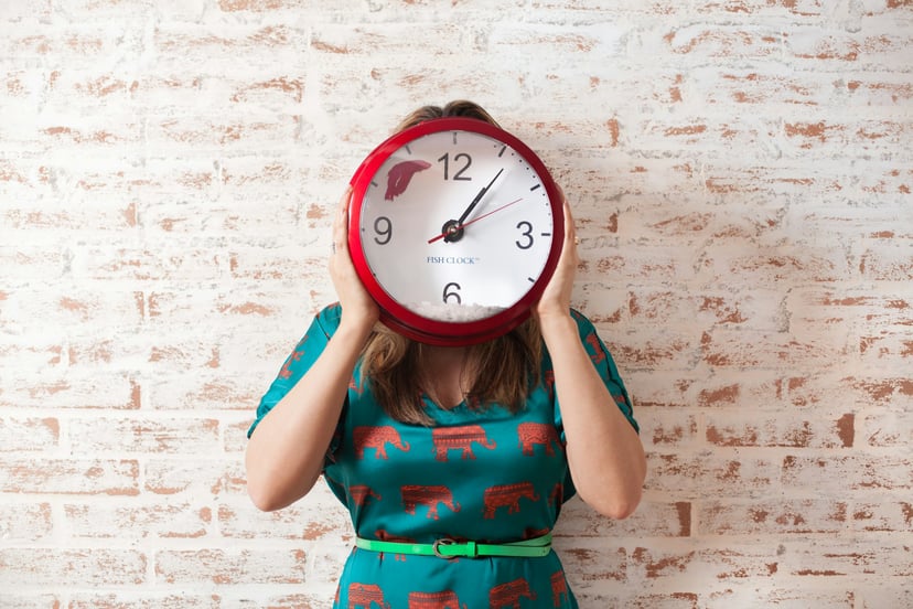 woman holding a clock in front of her face