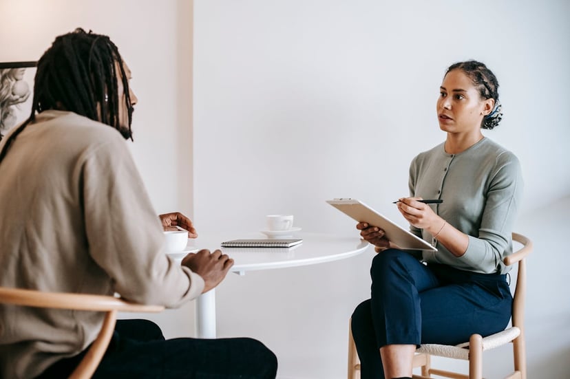 a woman holding a clipboard while interviewing a man 