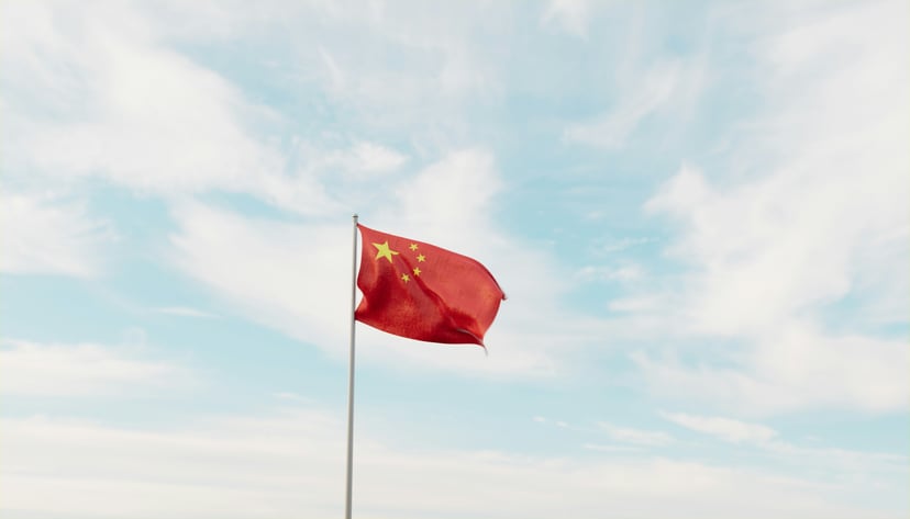 The flag of China flying against a blue sky with fluffy white clouds