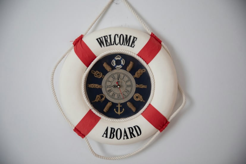A life buoy with 'welcome aboard' printed on it and a nautical clock in the center
