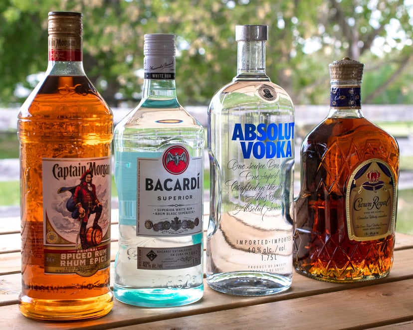 bottles of Captain Morgan rum, Bacardi, Absolut Vodka an Chivas Regal on a bench outside
