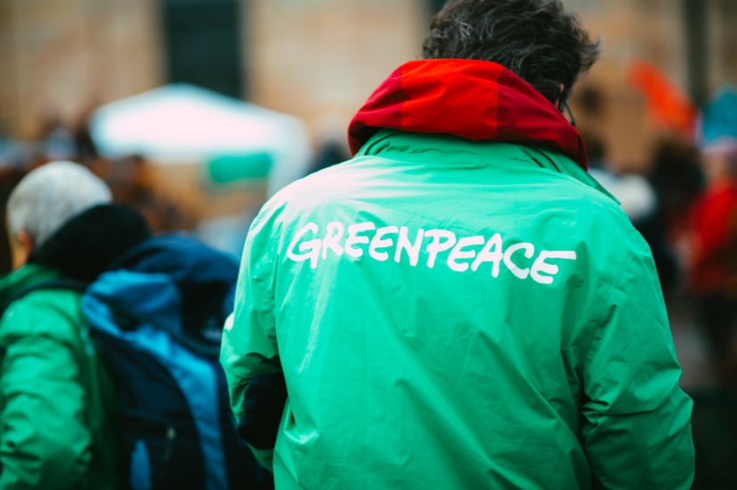 A person wearing a green Greenpeace jacket