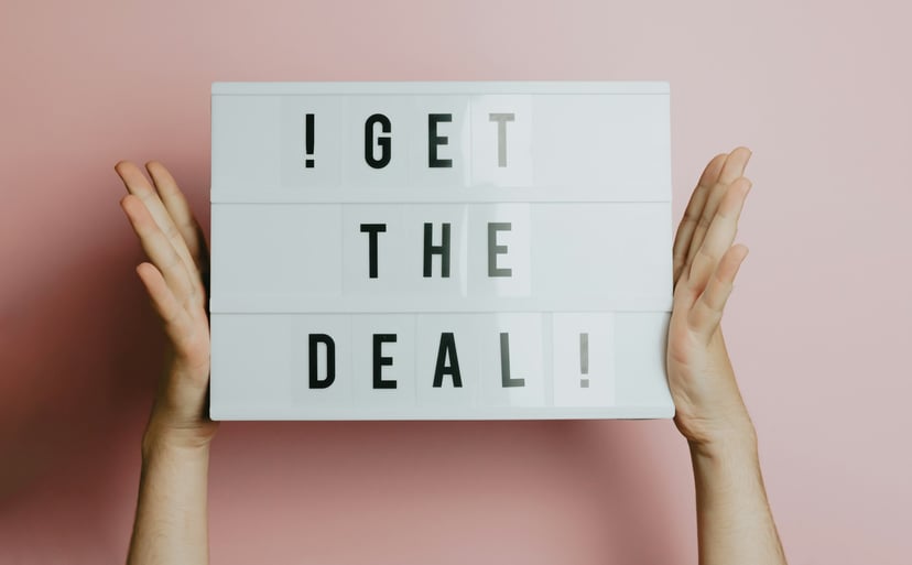 Hands holding sign that says 'get the deal'