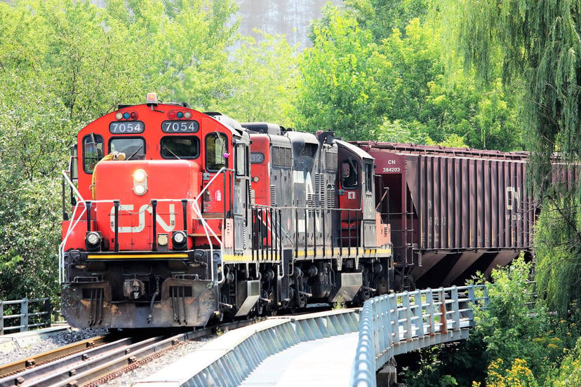 A  train engine pulling shipping containers through woods