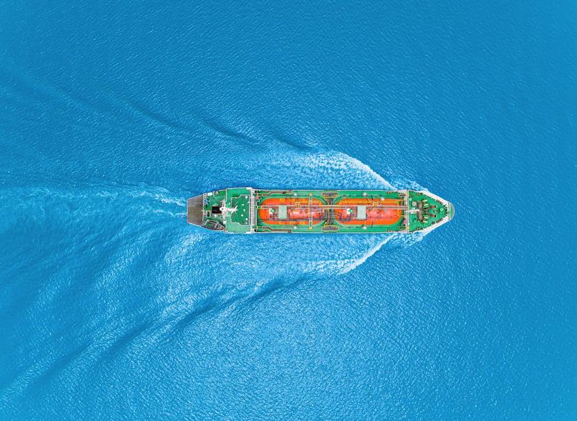 an aerial view of an orange and green gas carrier at sea