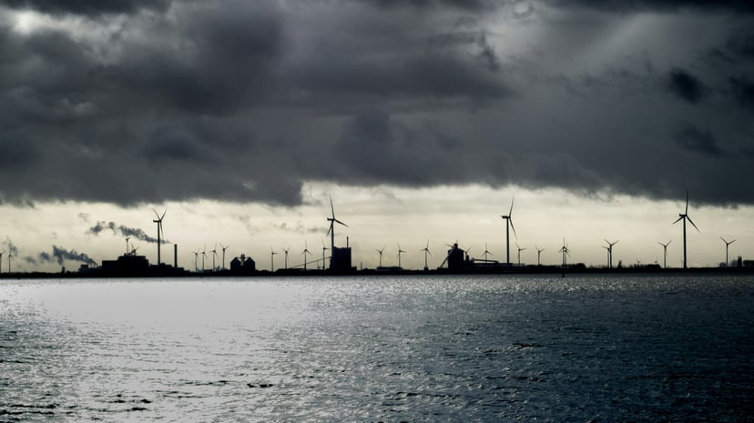 The German port of Emden seen from across the water with air turbines and a vessel in silhouette