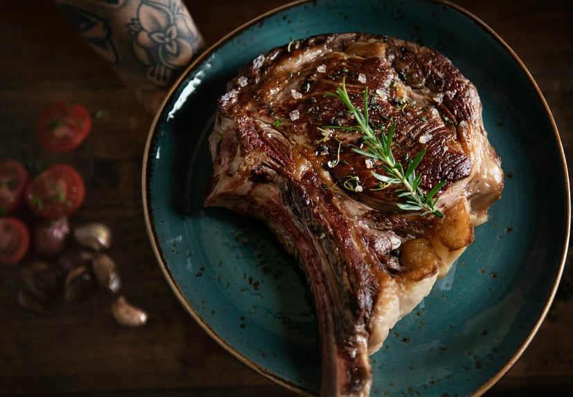 A steak garnished with thyme on a plate