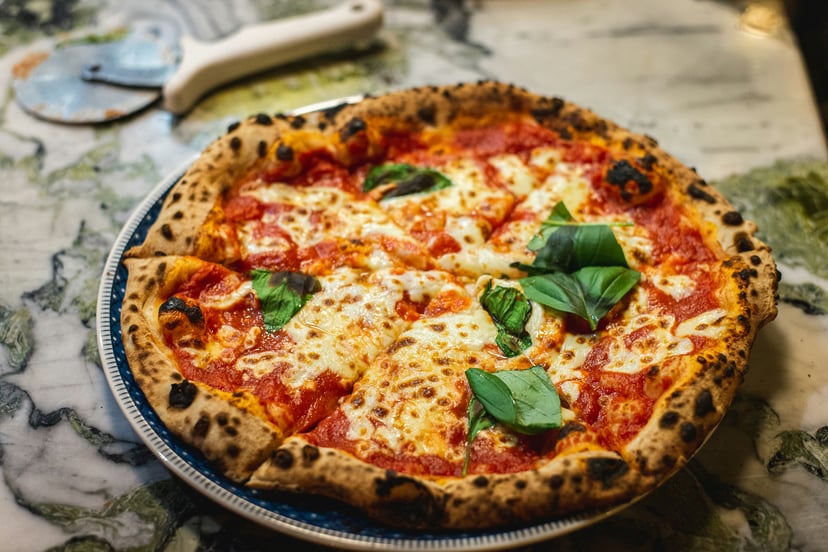 A pizza on a table next to a pizza cutter