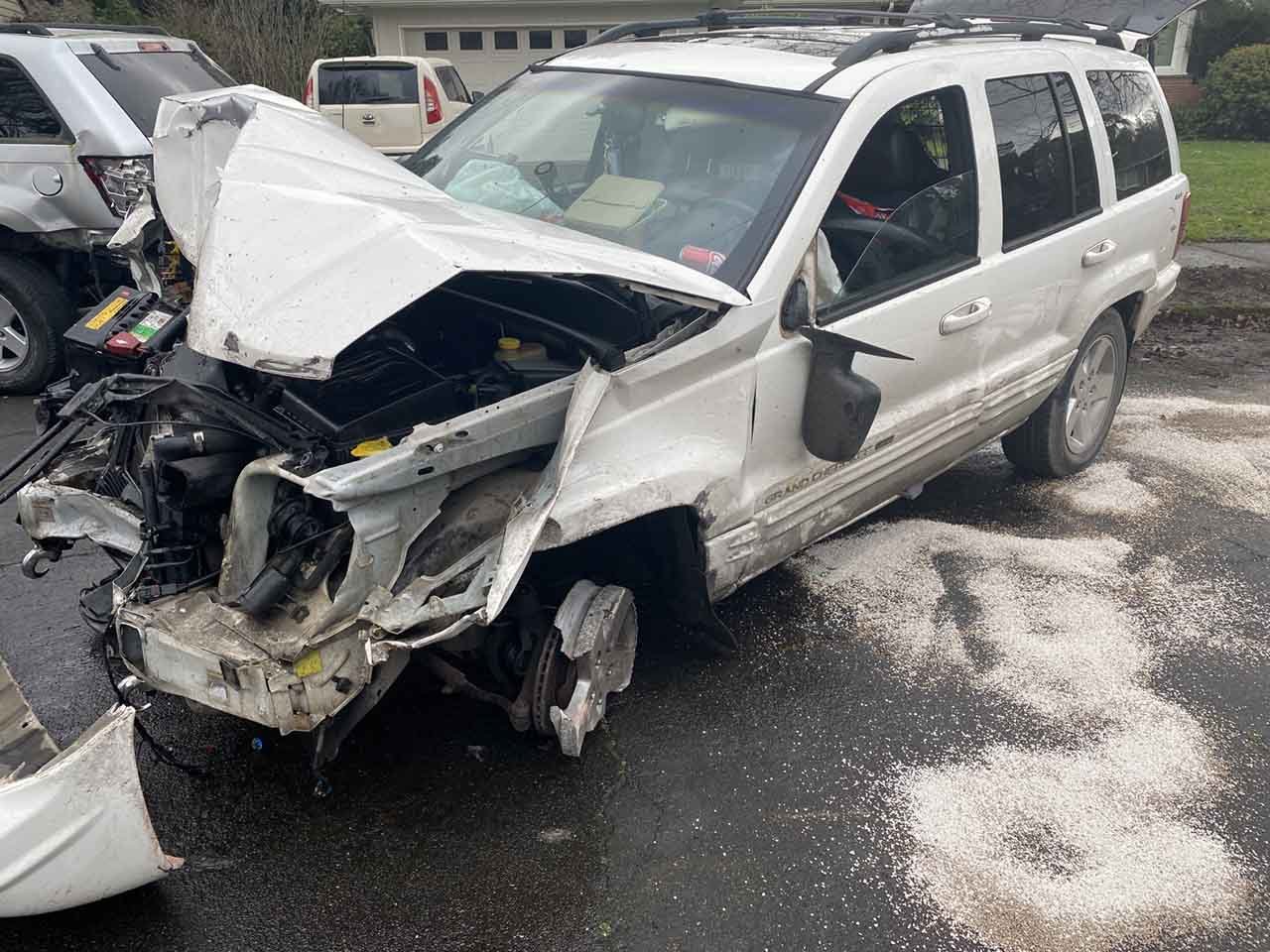 White SUV with heavy front end damage and a front left wheel worn down to the hub