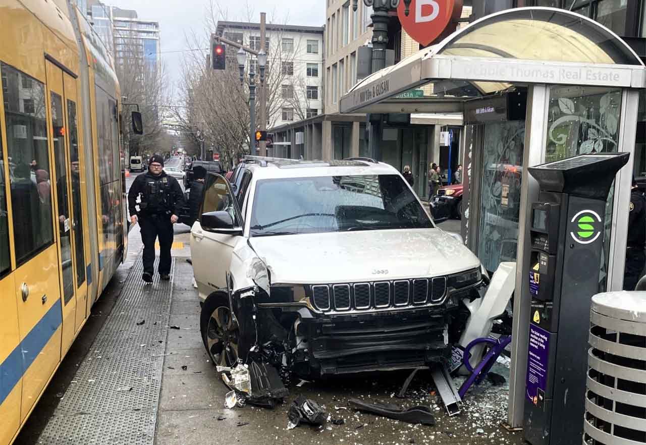 A Portland officer investigates a white Jeep SUV with heavy front end damage
