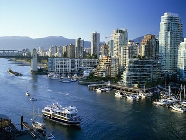 A boat cruises past a marina and downtown buildings, Vancouver