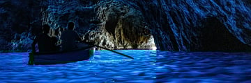Blue water in a cave with a boat on it