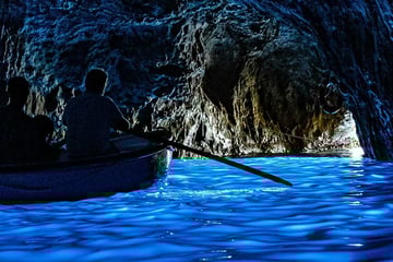 Blue water in a cave with a boat on it