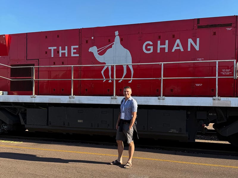 Programme Director, Chris, standing in front of The Ghan train