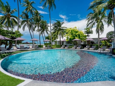 Pool area surrounded by palm trees at  La Vida Samui