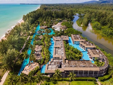 Aerial view of a resort surrounded by greenery and the beach