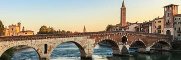 Bridge across a river with buildings on the other side at sunset