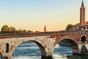 Bridge across a river with buildings on the other side at sunset