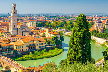 View of Verona's skyline with trees and a river in the foreground