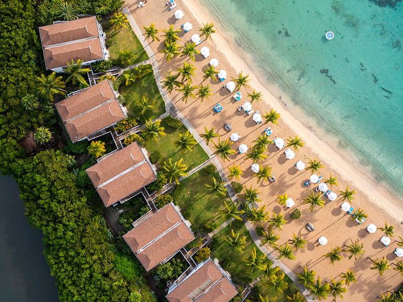 An aerial view of Carlisle Bay, with big villas leading onto a beach with sunloungers