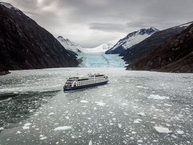 Australis Cruise Ship sailing past alpine landscapes