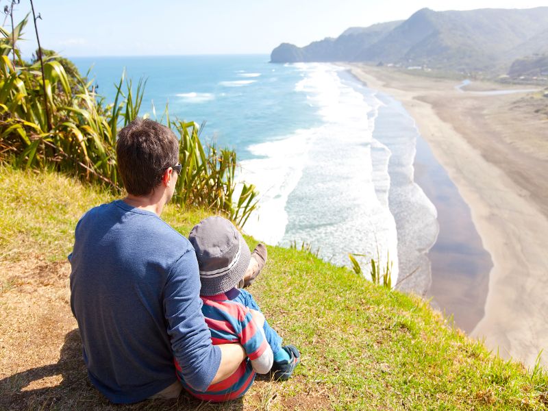 dad and son looking over piha beach