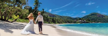 Married couple walking along the beach at Kempinski 