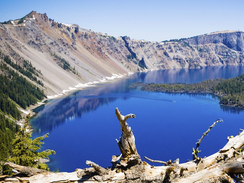 Small boat on calm sapphire waters of Crater Lake