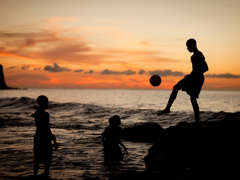 children playing football at sunset in St Kitts