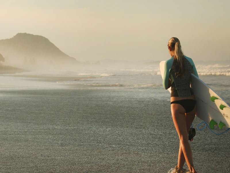 Surfer walking on the beach in the Bay of Plenty