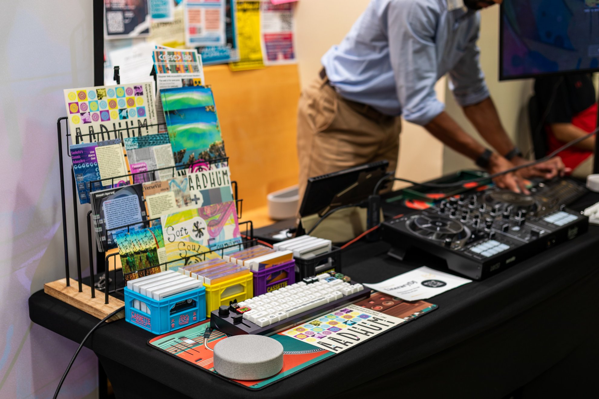 A host leaning over the table of controllers, keycaps and postcards.