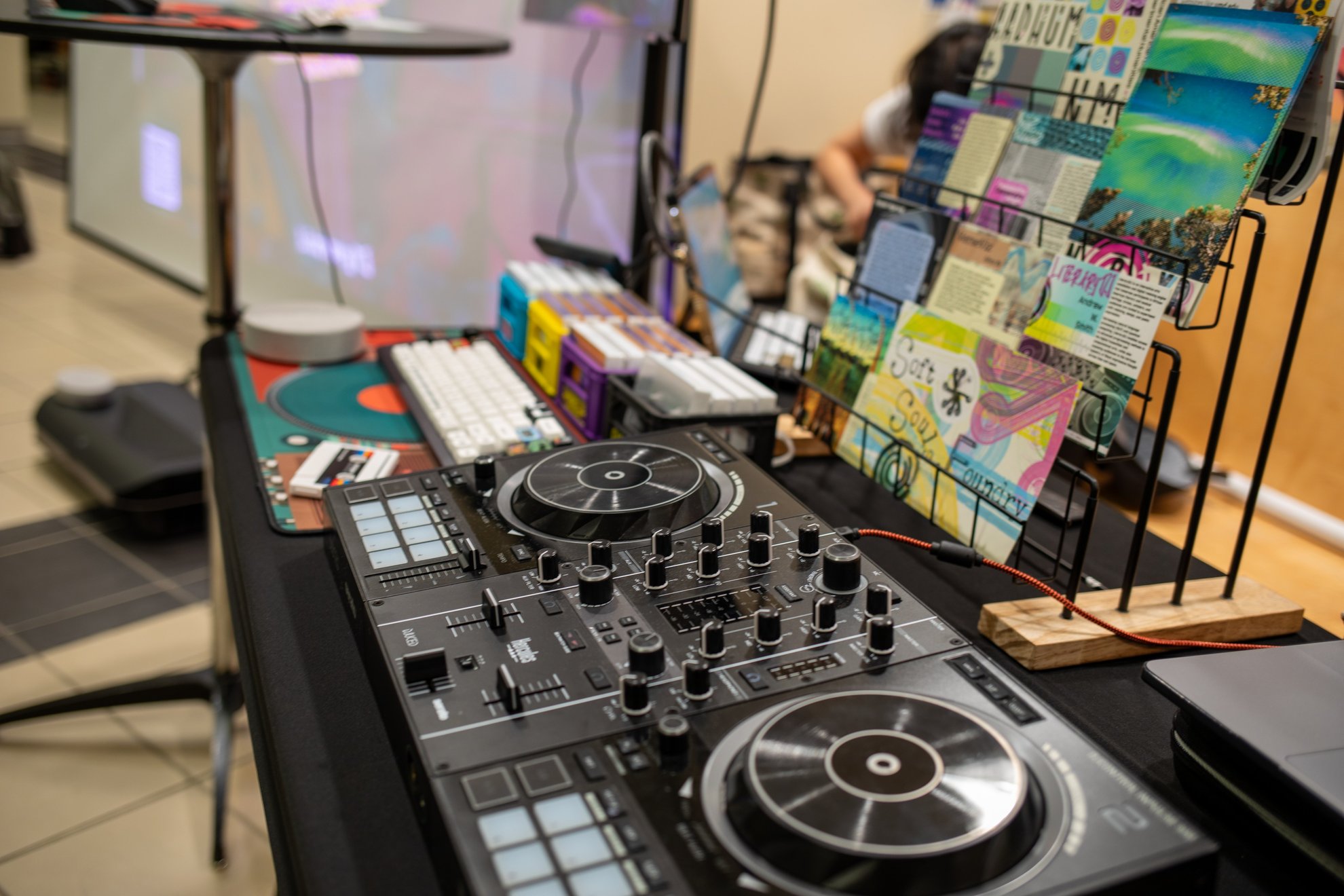 The DJ controller on the table beside a rack of postcards.