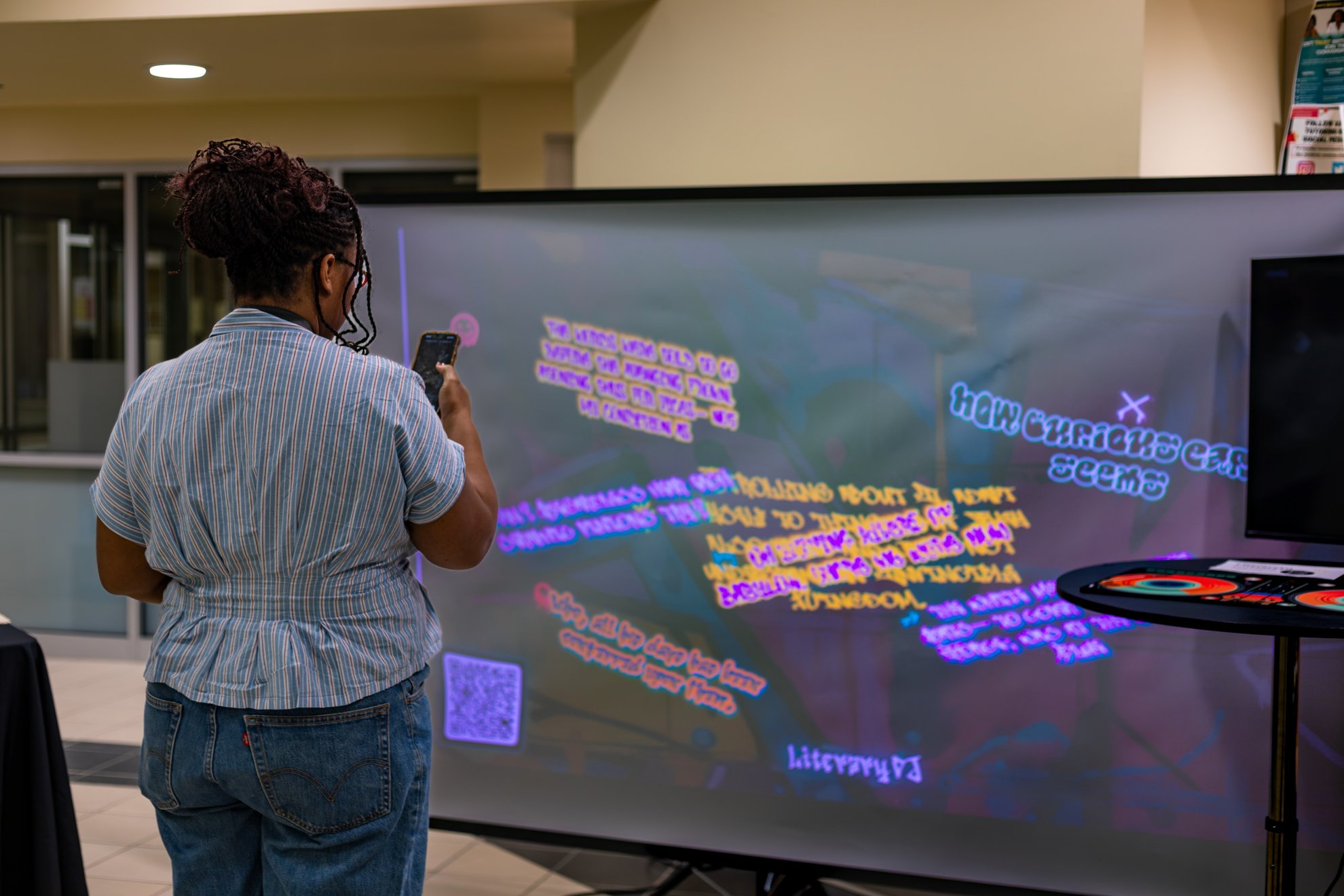 A visitor holding up a phone to a projected wall of lines.