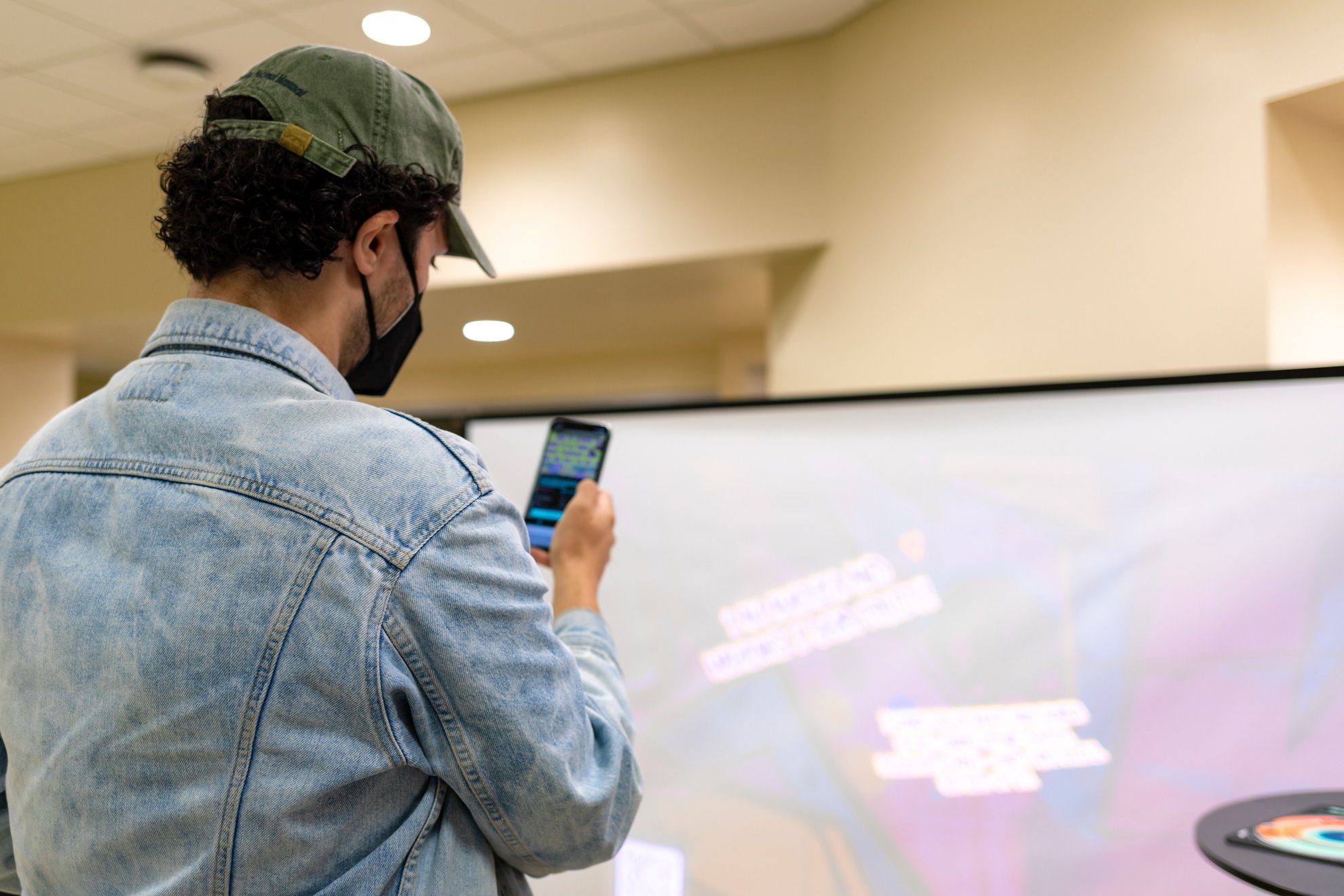 A visitor holding up a phone to see the wall in AR.
