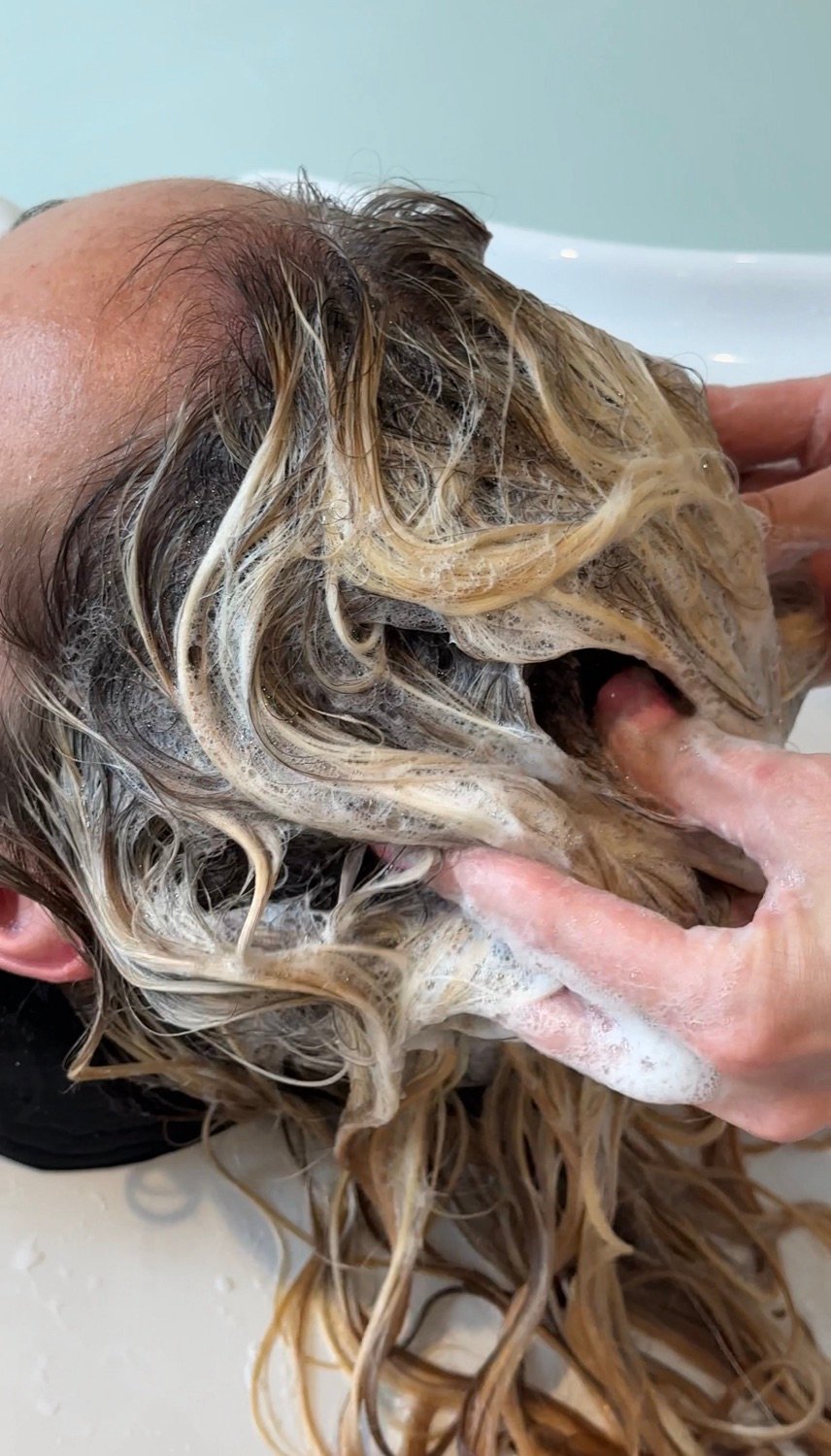 Coloristin arbeitet Gloss und Toner in nasses blondiertes Haar ein