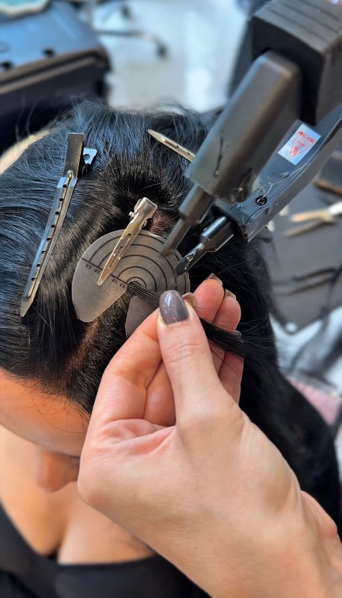 Bonding Extensions werden mit Wärmezange in schwarzes Haar eingearbeitet