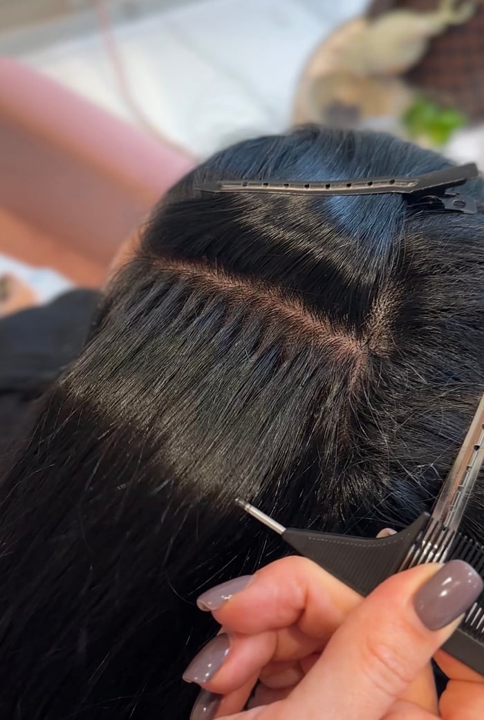 Nahaufnahme mehrerer Reihen Keratin-Bondings im schwarzen Haar