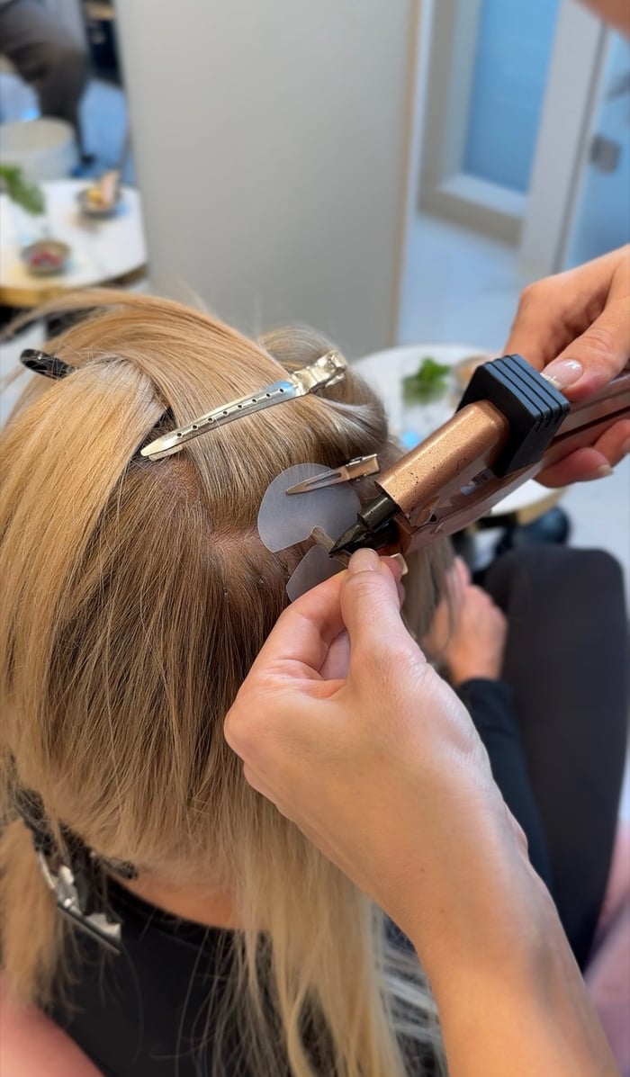 Tape-In Extensions werden am blonden Haaransatz angebracht